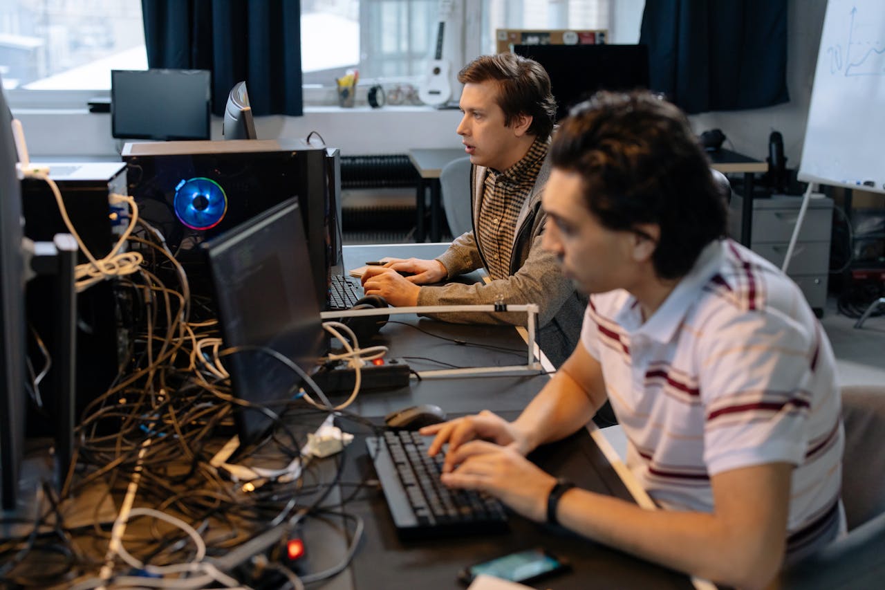 Male programmers working on computers in a modern office setting, showcasing teamwork and technology.